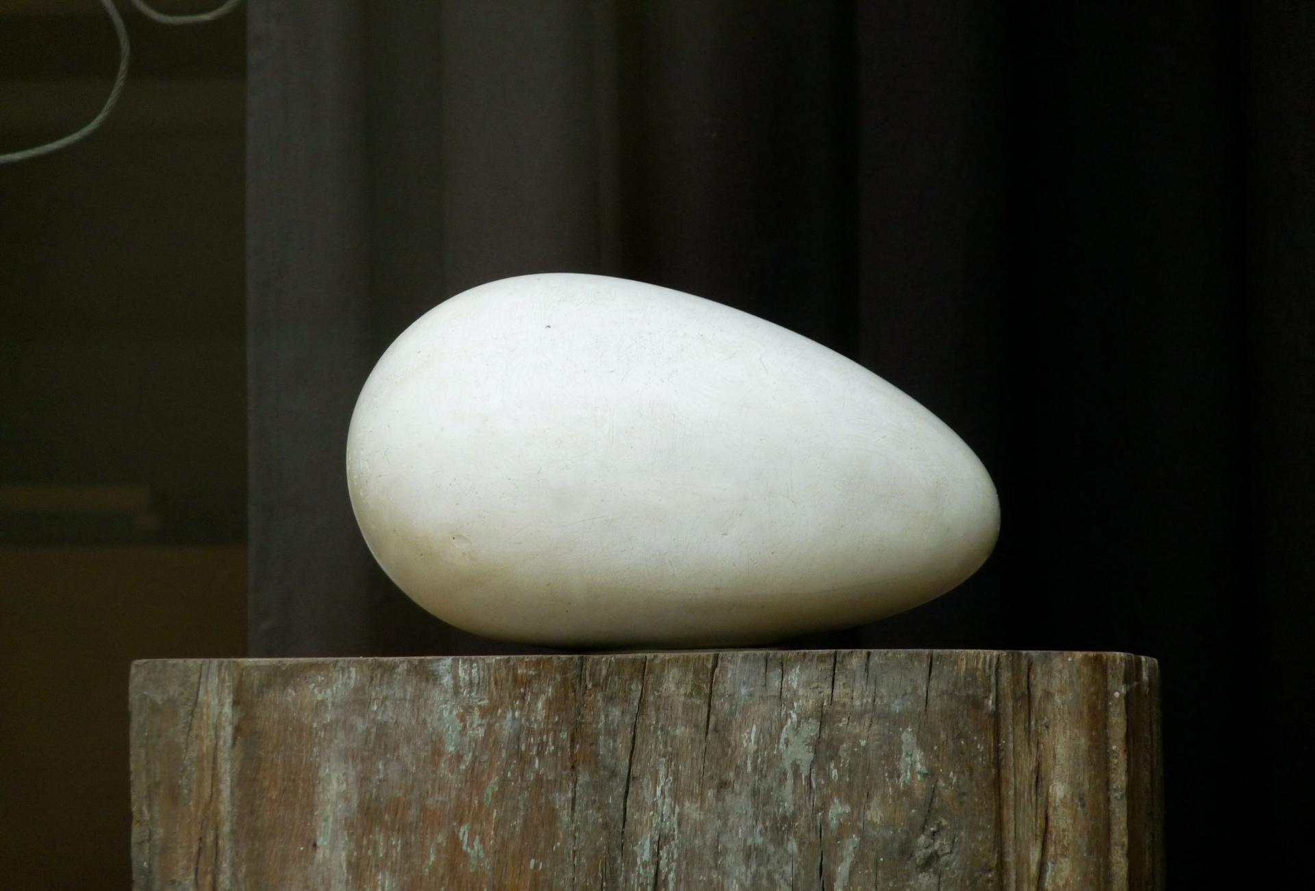 Sculpture de Brancusi. Une forme ovale en pierre blanche pure posé. Symbole de créativité et de naissance. sur une souche d'arbre brute.