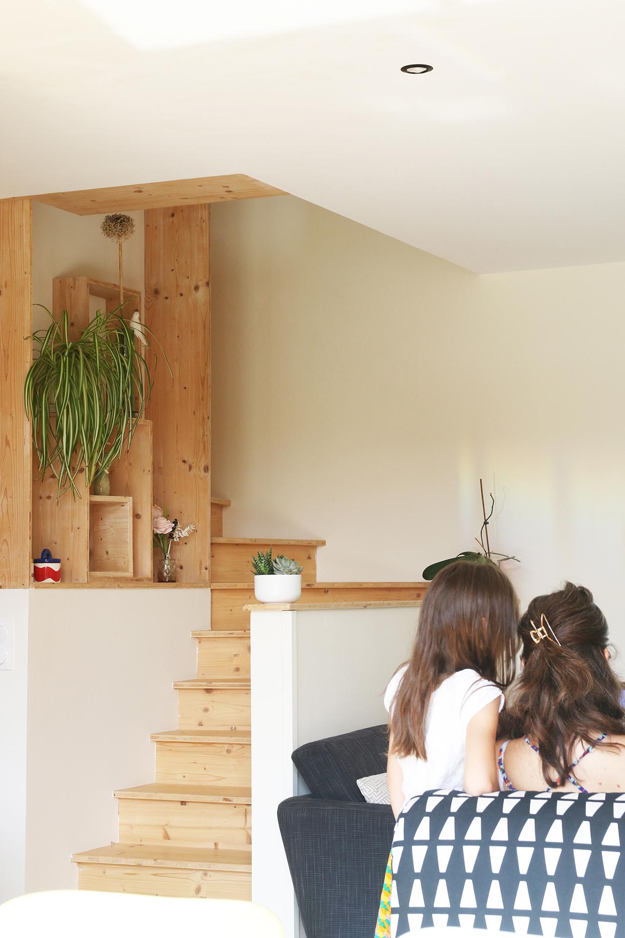 L'escalier bibliothèque trouve sa place au milieu de la maison à ossature bois à Haute-Goulaine. 