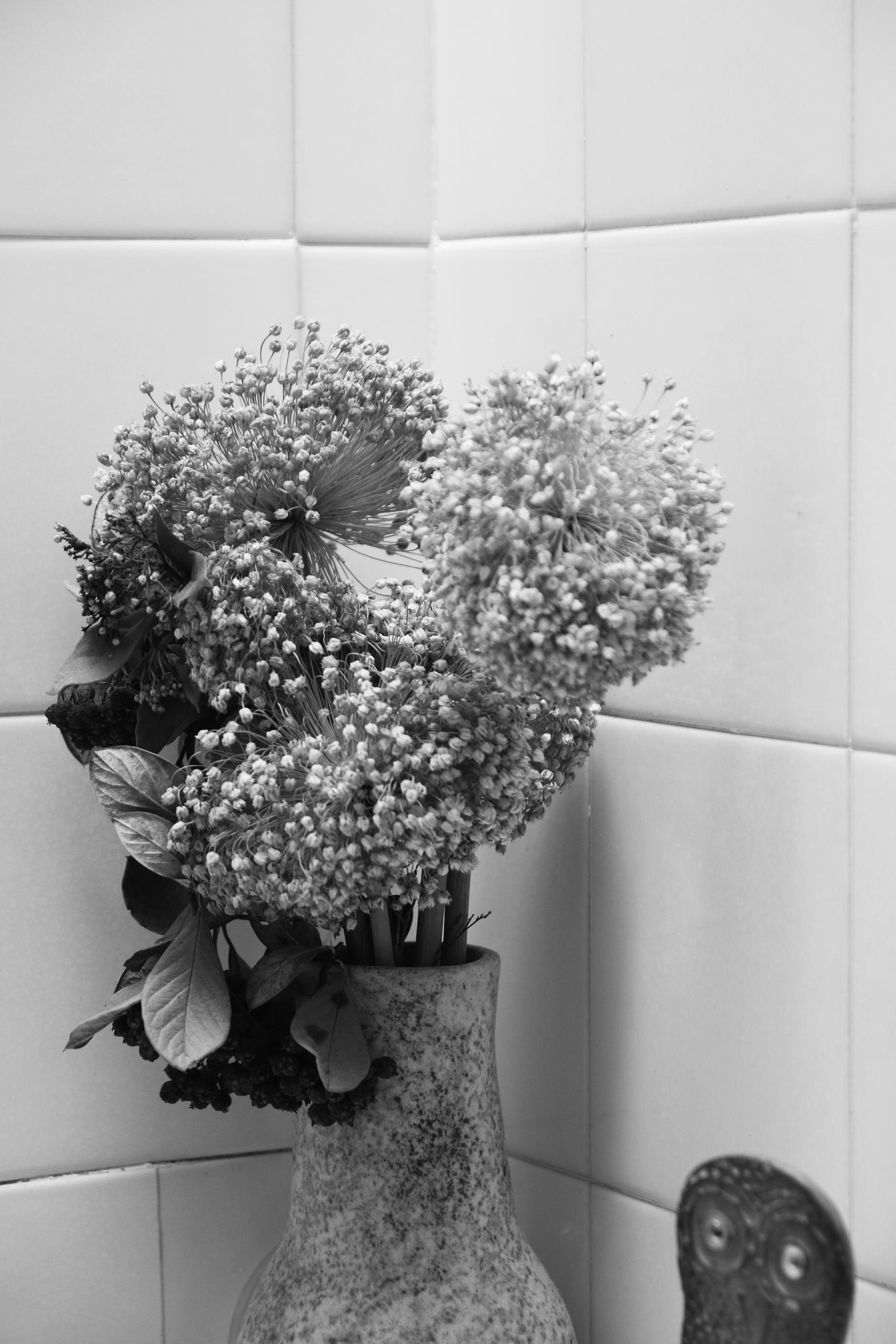 Détail sur un vase en céramique émaillé vert émeraude dans lequel il y a un bouquet de fleurs séchées dans la salle de bain très lumineuse dessinée par Jérôme Barrier à Vertou en Loire-Atlantique. 