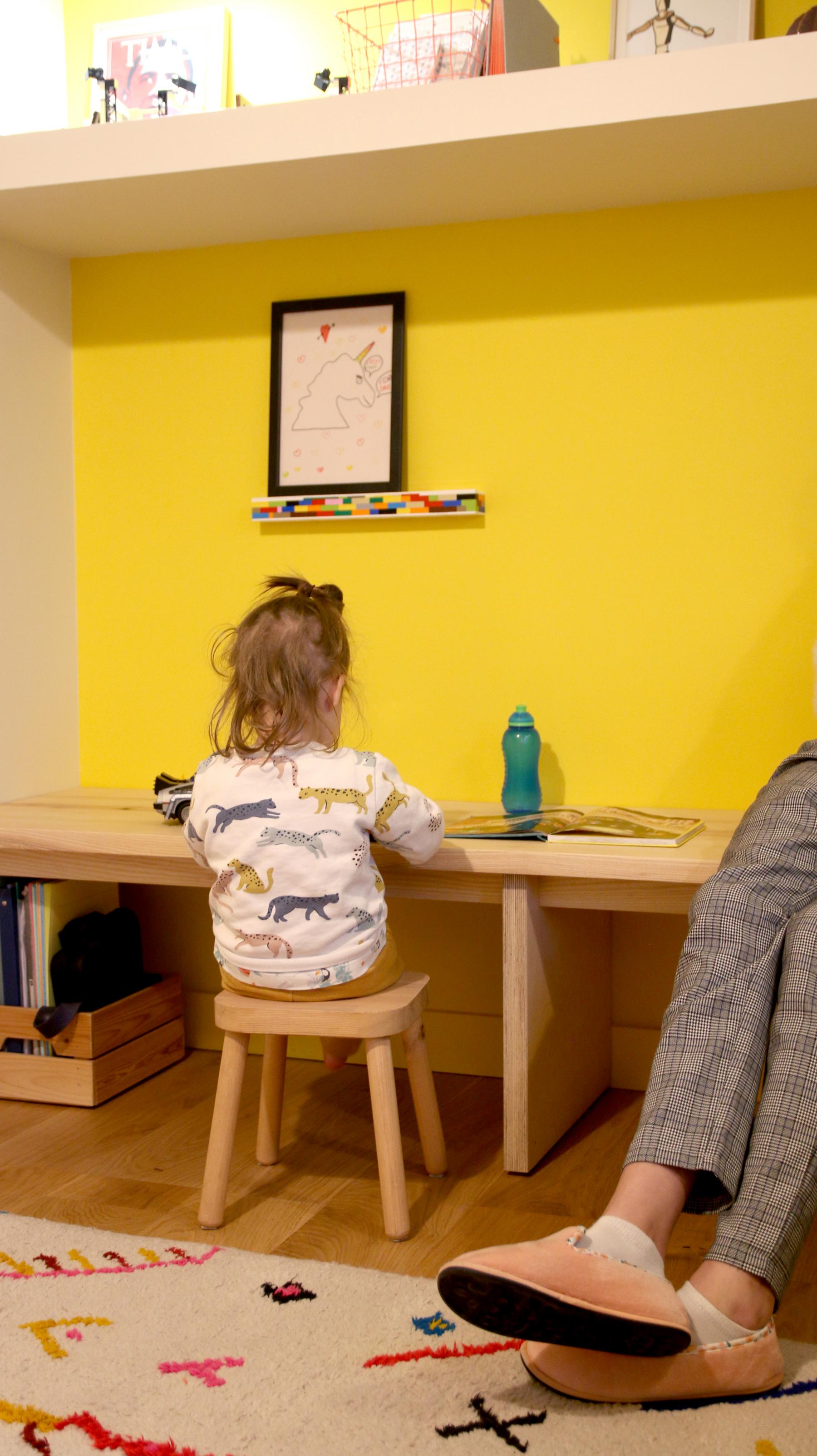 L'enfant est assis sur le bureau adapté à sa taille en frêne massif. Créations sur mesure à Vertou Nantes Loire-Atlantique. Réalisation artisans locaux. 
